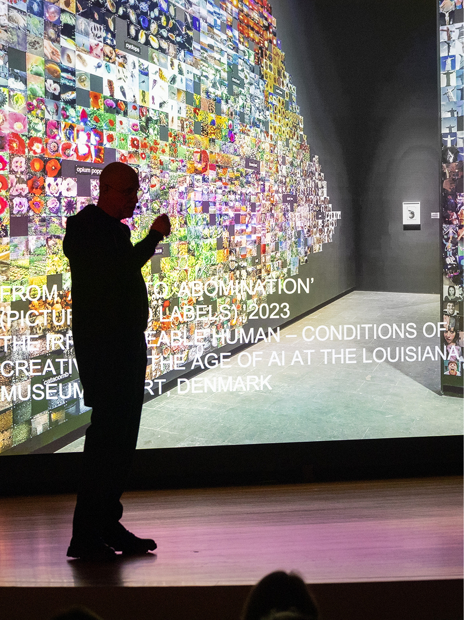 Trevor Paglen speaking at the Guggenheim Museum public program with “From ‘Apple’ to ‘Abomination’” in the background