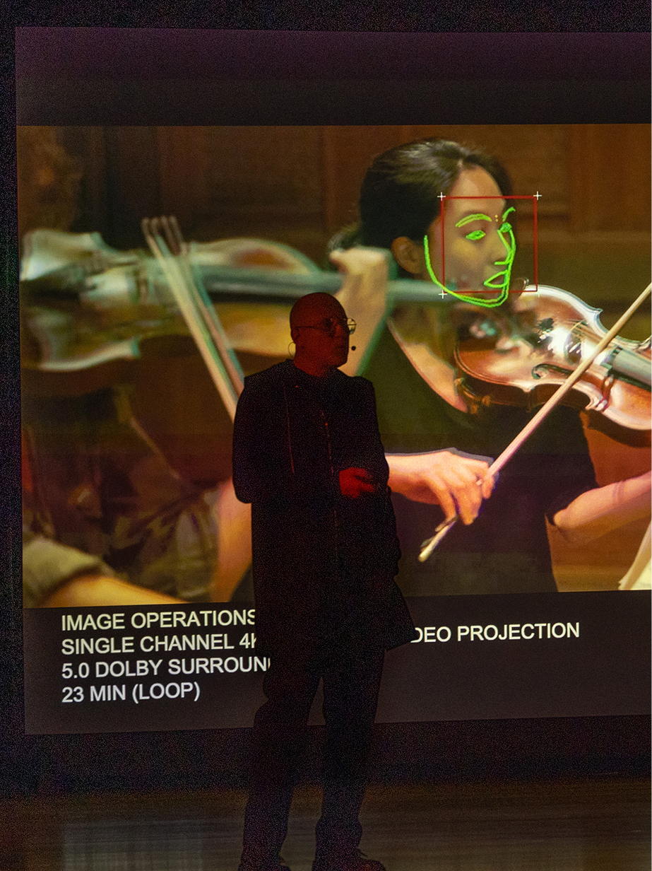 Trevor Paglen speaking at the Guggenheim Museum public program with “Image Operations” in the background